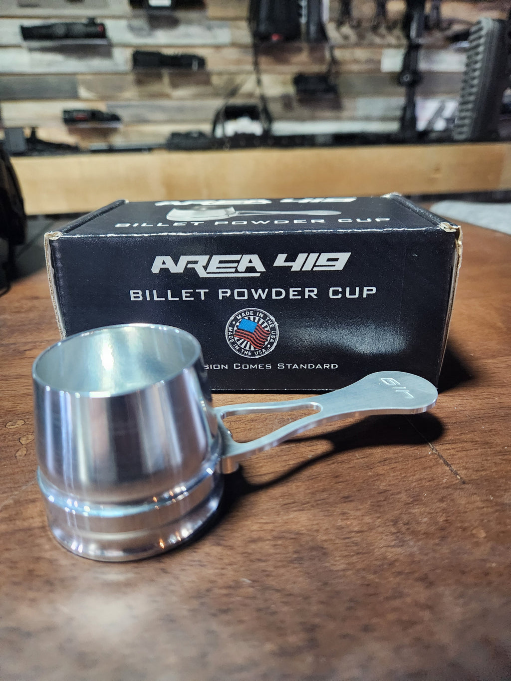 A black billet powder cup with the Area 419 logo, shown in use with a firearm.
